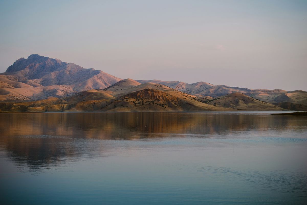 Kahle Hügel spiegeln sich in der Abenddämmerung in einem stillen See